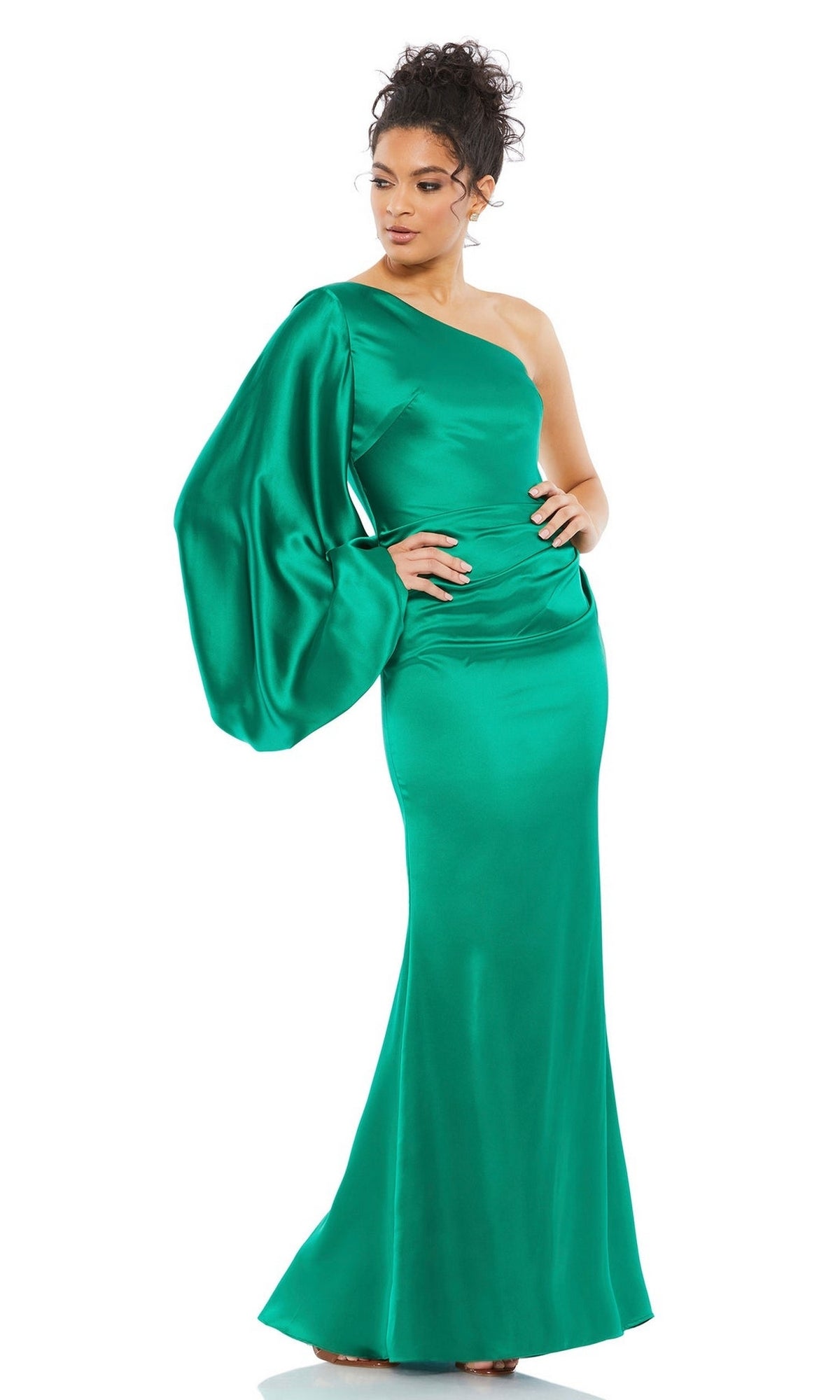 A woman in the Mac Duggal 26588 One-Sleeve Long Formal Dress, a shiny emerald green gown with dramatic long sleeve and fitted floor-length skirt.
